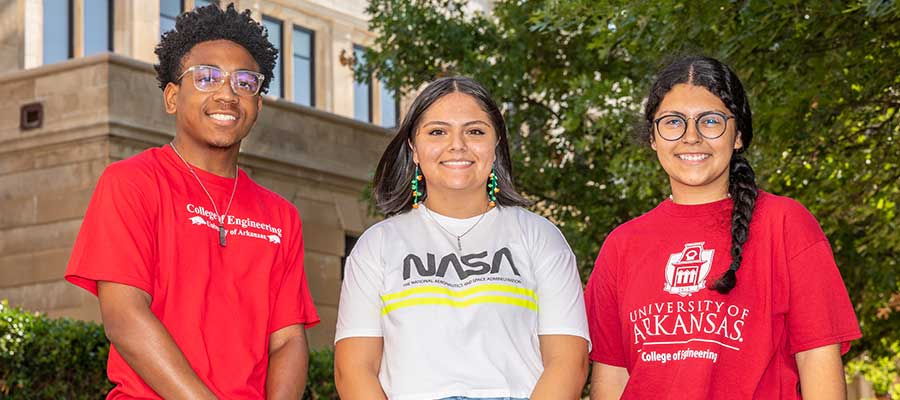 three students pose in front of engineering bulding